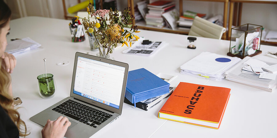 Person working on a desk with a laptop and a Bauhaus book.