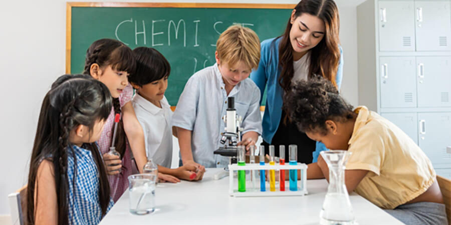 Chemistry teaching assistant with a group of children with a microscope and test tubes.