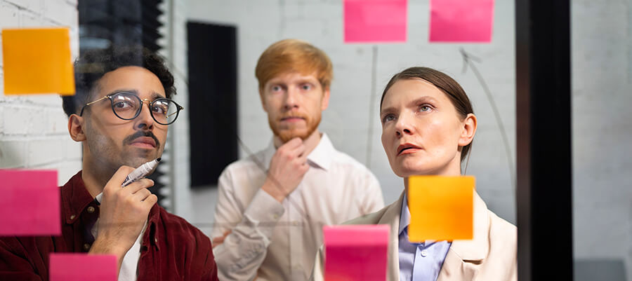 Colleagues looking puzzled at some post it notes stuck to a glass door.