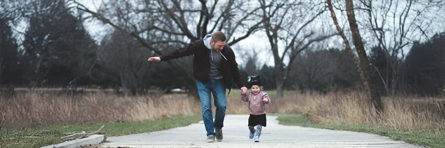 Father running with his young daughter while holding her hand.