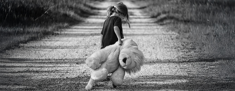 Girl with large plush toy on a gravel road.