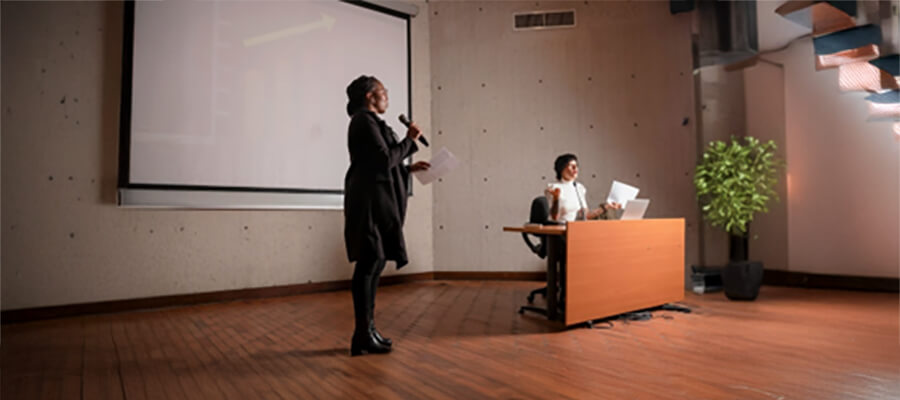 Person giving a speech in front of a white board.