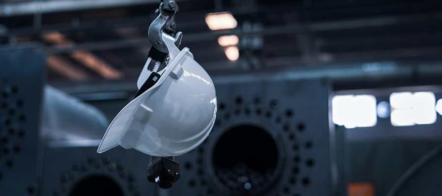 White hard hat hanging on an industrial hook.
