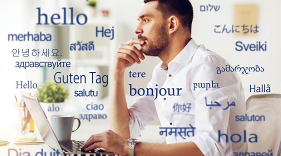 Man looking at laptop with 'hello' in many different languages.