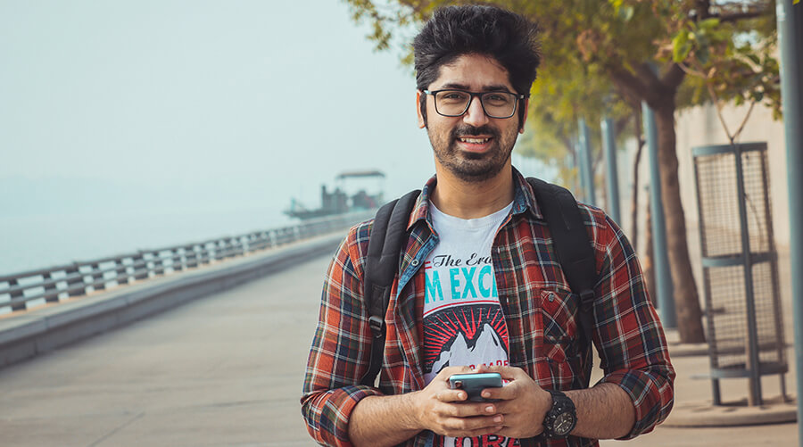 Man with his phone on the boardwalk at the coast.