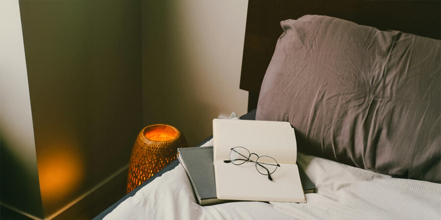 Notepad and glasses on a bed.