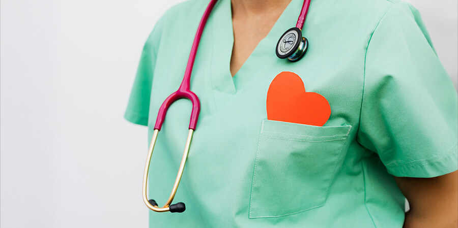 Nurse with a green uniform and a paper heart in her top pocket.