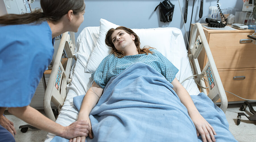 Nurse talking to a patient in a hospital bed.