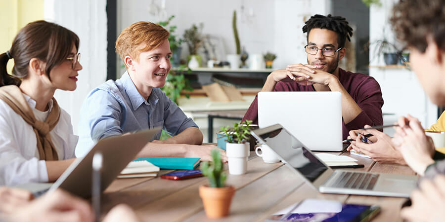 Group of people sitting around a desk having an planning meeting.