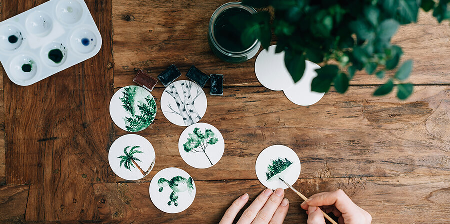 Creative person painting plants onto white disks.