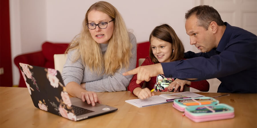 Parents helping their daughter with homework.