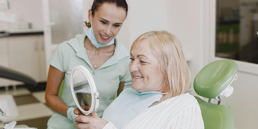Dental patient admiring her teeth in a mirror.