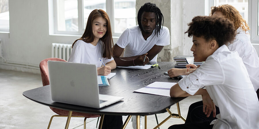 Group of people sitting around an oval desk having a remote meeting.