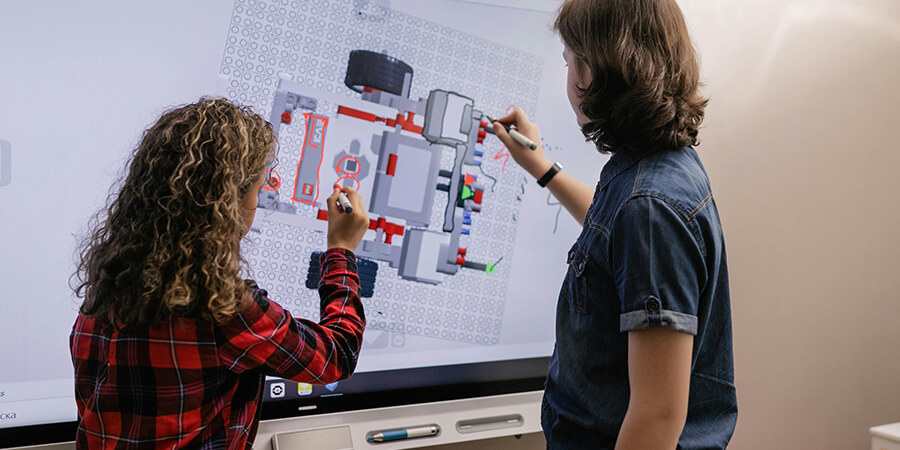 Two people drawing on an interactive screen.