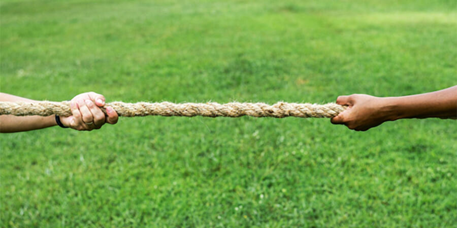 Two arms pulling a rope in a tug-of-war.