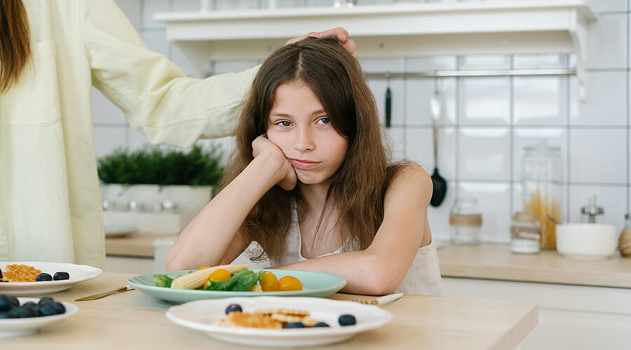 Unhappy looking girl child with a plate of food.