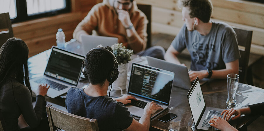 Group of young professionals working on laptops around a table.